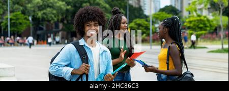 Junger afro-amerikanischer Student mit einer Gruppe junger Erwachsener im Sommer in der Stadt Stockfoto