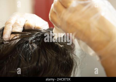 Eine reife kaukasische Frau, Latina Frau färbt ihre Haare zu Hause, trägt Handschuh Stockfoto
