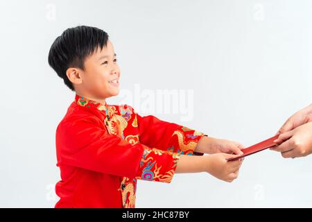 Asiatischer vietnamesischer Junge, der auf dem Mond-Neujahrsfest rote Papiertüten oder Geld von einem anderen erhält, wobei das traditionelle Ao dai auf weißem Hintergrund isoliert ist Stockfoto