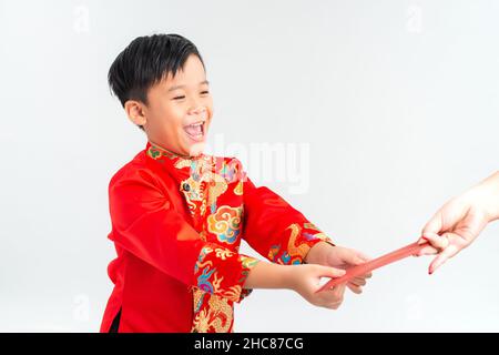 Asiatischer vietnamesischer Junge, der auf dem Mond-Neujahrsfest rote Papiertüten oder Geld von einem anderen erhält, wobei das traditionelle Ao dai auf weißem Hintergrund isoliert ist Stockfoto