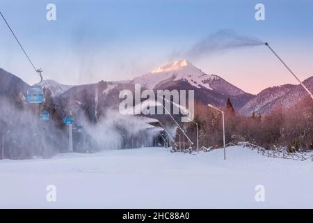 Bansko, Bulgarien - 21. Dezember 2021: Bulgarisches Winter-Skigebiet-Panorama mit Gondelbahnen Kabinen, Blick auf die Pirin Berggipfel und Piste Stockfoto