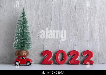 Kleiner Weihnachtsbaum steht auf dem Spielzeugauto neben dem 2022sign. Speicherplatz kopieren. Stockfoto