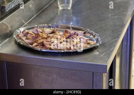 Tablett mit lila Kartoffelchips auf einem Edelstahltisch Stockfoto