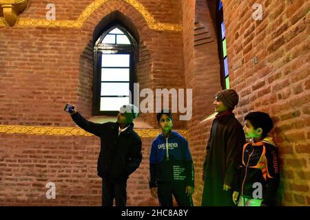 Srinagar, Indien. 25th Dez 2021. Muslimische Jungen machen am Weihnachtstag in Srinagar ein Selfie in der St. Lukes Kirche.nach drei Jahrzehnten wurde die 125 Jahre alte St. Luke Kirche, die nach der wachsenden Gewalt in den Jahren 1990s verwüstert blieb, renoviert und an Weihnachten für die Gläubigen geöffnet. Christen in Indien und auf der ganzen Welt feiern Weihnachten, um der Geburt Jesu, der zentralen Figur des Christentums, zu gedenken. Kredit: SOPA Images Limited/Alamy Live Nachrichten Stockfoto