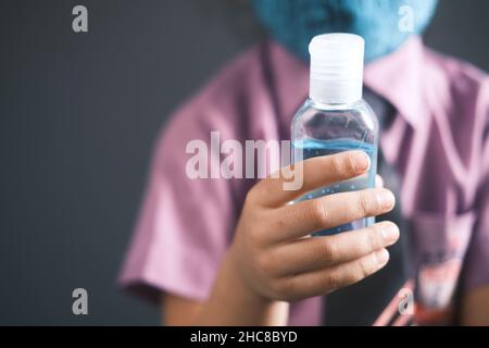Kind Mädchen in Schulkleidung mit Handdesinfektionsmittel mit Kopierraum Stockfoto