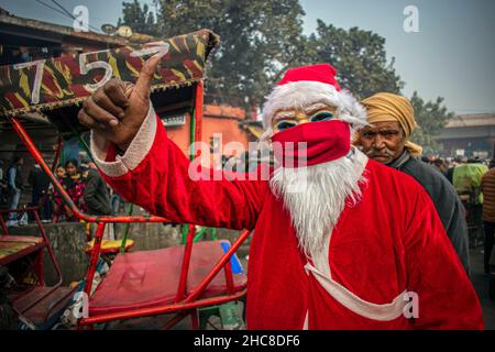 Neu-Delhi, Indien. 25th Dez 2021. Ein Mann, der als Weihnachtsmann gekleidet ist, verteilt Süßigkeiten an alle in den alten Vierteln von Delhi, Indien.Weihnachten ist ein jährliches Fest zur Erinnerung an die Geburt Jesu Christi, das hauptsächlich am 25. Dezember als religiöses und kulturelles Fest unter Milliarden von Menschen auf der ganzen Welt gefeiert wird. (Foto: Mohsin Javed/Pacific Press/Sipa USA) Quelle: SIPA USA/Alamy Live News Stockfoto