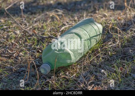 Verschmutzung durch Plastik. Plastikflasche mit Reif bedeckt liegt im Wald. Nahaufnahme Stockfoto