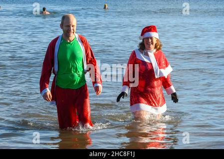 Paignton, Devon, Großbritannien. 26th. Dezember 2021. Wetter in Großbritannien. Schwimmer in festlicher Kleidung gehen am zweiten Weihnachtsfeiertag ins Meer, um an einem für die Saison unheimlich warmen, sonnigen Tag im Lion’s Club am Strand von Paignton in Devon ins Meer zu gehen. Bildnachweis: Graham Hunt/Alamy Live News Stockfoto