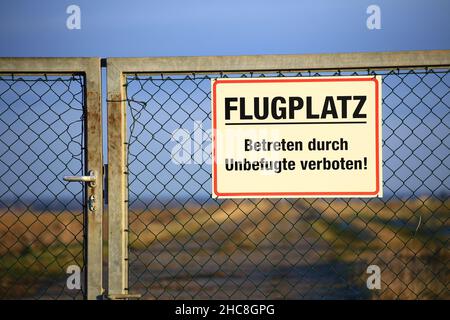 Schild an einem A-Tor mit der Aufschrift Flugplatz - Betreten durch unbefugte verboten (Airport - No Trespassing by unauthorized personnel). Stockfoto