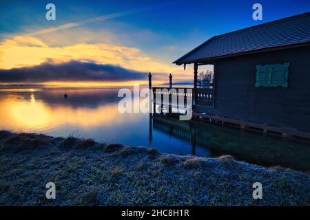 Blick auf den Starnberger See, Bayern und ein hölzernes Bootshaus bei Sonnenuntergang Stockfoto