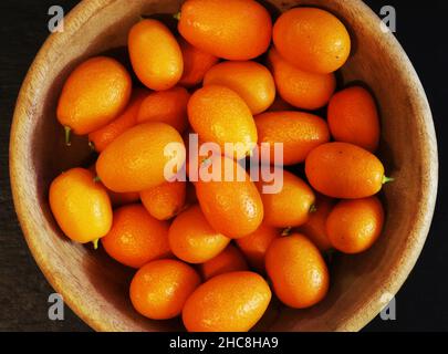 Fotografie von Kumquats in einer Holzschale zur Verbildnung von Lebensmitteln Stockfoto