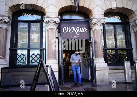 Ein Mann mit Gesichtsmaske verlässt einen Zweig von O'Neill in Cardiff, Wales, da neue Covid-19-Regeln in Kraft treten. Gruppen von maximal sechs Personen dürfen sich in Pubs, Kinos und Restaurants in Wales treffen, wobei in öffentlichen Räumlichkeiten und Büros eine soziale Distanzierung von zwei Metern erforderlich ist. Bilddatum: Sonntag, 26. Dezember 2021. Stockfoto