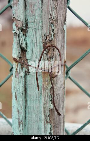 Verrosteten alten Draht um eine Holzdiele mit einem losen Knoten gewickelt. Stockfoto