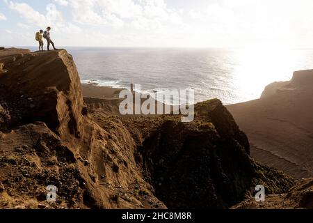 Mutter und Sohn stehen auf einem Aussichtspunkt über dem Vulkan Capelinhos und dem Leuchtturm, Ponta dos Capelinhos, Faial, den Azoren, Portugal Stockfoto