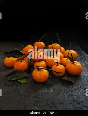 Mandarinen auf einem schwarzen Tisch mit schwarzem Hintergrund Stockfoto