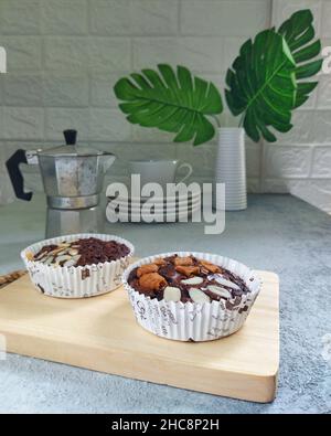 Brownies auf einem Schneidebrett, Mokapot, eine Tasse Kaffee und Pflanzen auf einem rustikalen Tisch Stockfoto