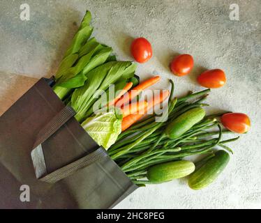 Gemüse; Bok Choy, chinakohl, Karotten, lange Bohnen, Gurken und Tomaten in einem schwarzen Beutel auf einem Tisch Stockfoto