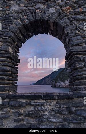 Felsige Berge an der Küste durch Steinbogenfenster gesehen. Italien, Ligurien, Portovenere Stockfoto