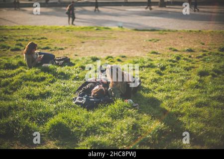Strahlender Sommertag in einem Park mit einem Paar, das auf dem üppigen Gras liegt und den Tag genießt Stockfoto