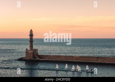 Oranger Himmel bei Sonnenuntergang mit Segelbooten am Leuchtturm des venezianischen Hafens in der Altstadt von Chania - Kreta Insel, Griechenland Stockfoto