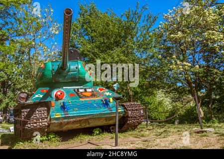 Alte Militärpanzer in bunten Herzen, Sternen und Blumen in einem Park gemalt Stockfoto