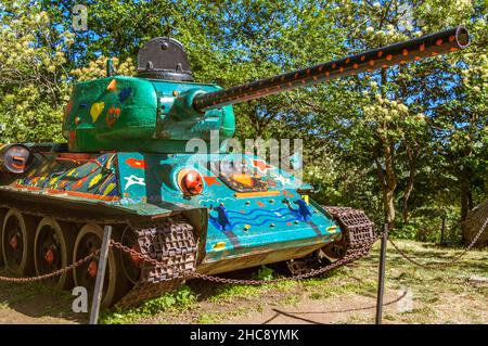 Alte Militärpanzer in bunten Herzen, Sternen und Blumen in einem Park gemalt Stockfoto