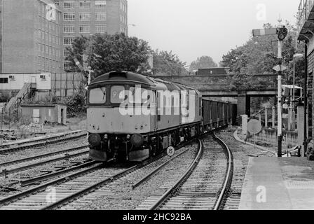 Ein Paar Diesellokomotiven der Klasse 33 mit den Nummern 33008 und 33019 fährt am 15th. Juli 1991 doppelt in einem Zug leerer Ballastwagen, der die Semaphore-Signale in Kensington Olympia passiert.