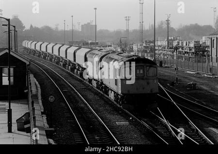 Ein Paar Diesellokomotiven der Klasse 33 mit den Nummern 33058 und 33064, die am 6th. November 1990 in einem Zug leerer MARCON-Waggons an der Acton Main Line vorbeifahren.
