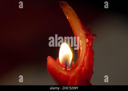 Makrofoto einer roten Wachskerze, die von ihrer heißen Flamme verzehrt wird Stockfoto
