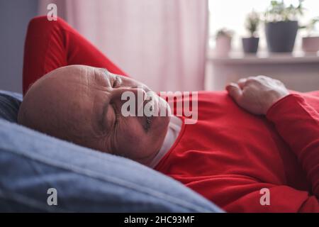 Der ältere Mann schlief morgens mit einem süßen Traum auf dem Bett im Schlafzimmer Stockfoto