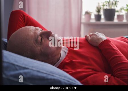 Der ältere Mann schlief morgens mit einem süßen Traum auf dem Bett im Schlafzimmer Stockfoto