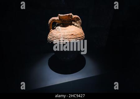 Die antike griechische Amphora wurde von Töpfern aus Ton hergestellt und zum Transport von Olivenöl und Wein verwendet. Beleuchtetes Artefakt auf dunklem Hintergrund Stockfoto