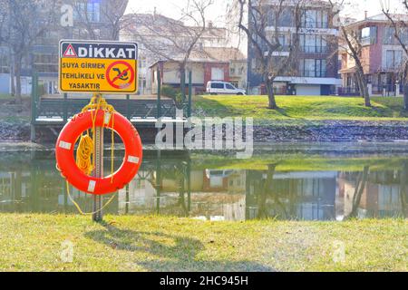 Rettungsboje und Warnschild am Flussufer an einem sonnigen Tag in der Türkei Stockfoto