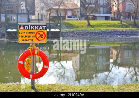 Rettungsboje und Warnschild am Flussufer an einem sonnigen Tag in der Türkei Stockfoto