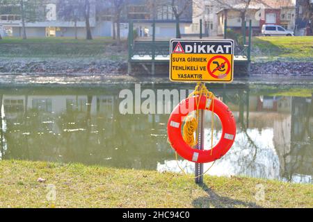 Rettungsboje und Warnschild am Flussufer an einem sonnigen Tag in der Türkei Stockfoto