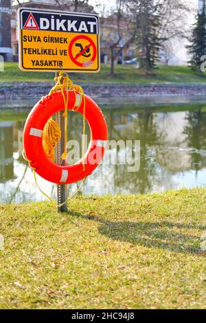 Rettungsboje und Warnschild am Flussufer an einem sonnigen Tag in der Türkei Stockfoto