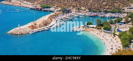 27. August 2021, Kalkan, Türkei: Badeort Kalkan in der Türkei. Leuchtturm am Eingang zum Yachthafen und Strand mit weißem Sand mit Urlaubern Stockfoto