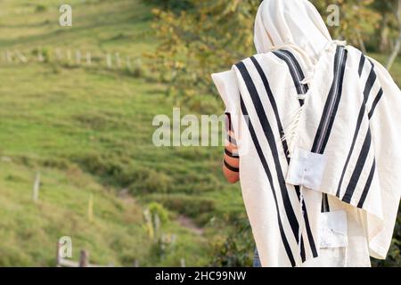 Jude trägt Tallit und Tefillin oder Mylakterie beten im Freien vor dem Hintergrund der Natur. Jude bedeckt seinen Kopf mit Tallit Stockfoto