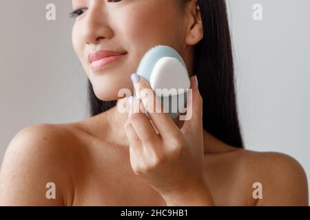 Asiatische junge Frau mit Gesichtsmassager im Studio Stockfoto