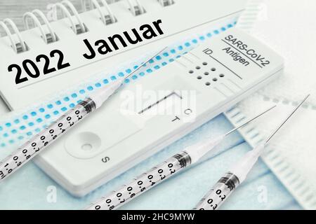 Deutscher Kalender 2022. Januar mit 3 Injektionen und Corona Rapid Antigen Test und FFP2 Maske Stockfoto