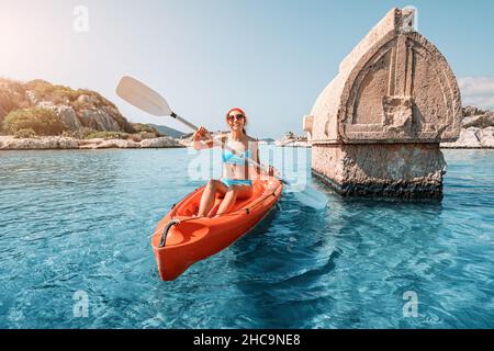 Mädchen auf einem Kajak erkundet ein uraltes lykisches Grab, das mitten in einer überfluteten Stadt nach einem schweren Erdbeben in der Nähe der Insel Kekova aus dem Wasser ragt Stockfoto