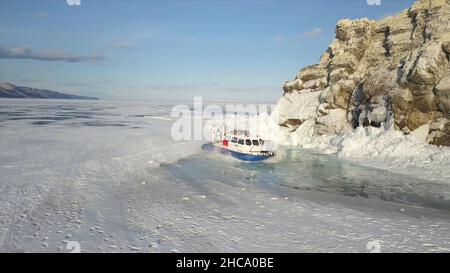 Die Menschen reisen auf dem Eis des gefrorenen Baikalsees in einem sicheren und komfortablen Khivus Hovercraft. Luftansicht der Maschine mit Luftkissenboden rutscht Stockfoto