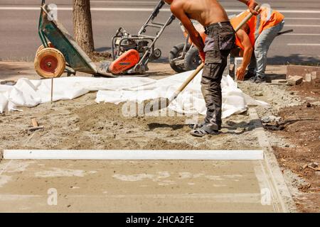 An einem Sommertag bereiten Hausangestellte eine Baustelle für die Verlegung von Pflasterplatten vor. Stockfoto
