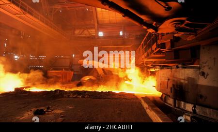 Heißer Stahl wird in die Rutsche im Stahlwerk gegossen, Schwerindustriekonzept. Produktion von geschmolzenem Stahl in Elektroöfen. Stockfoto