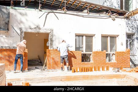 Zwei Arbeiter, die auf einer Hausbaustelle in Almaty, Kasachstan, Ziegelsteine an eine neue Wand legen Stockfoto