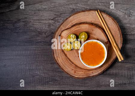 Gemahlene Chilisauce und Limettenscheiben auf einem hölzernen Schneidebrett. In der Regel für zusätzliche Würze für Fleischbällchen, Nudeln, Vermicelli usw. Stockfoto