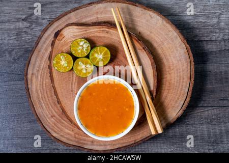 Gemahlene Chilisauce und Limettenscheiben auf einem hölzernen Schneidebrett. In der Regel für zusätzliche Würze für Fleischbällchen, Nudeln, Vermicelli usw. Stockfoto