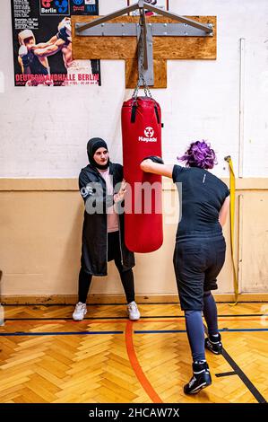 16. Dezember 2021, Berlin: Boxtrainerin Doha Taha Beydoun trainiert mit einer ihrer Boxer. Sie ist erst 20 Jahre alt. Verheiratet. Vier Monate schwanger. Muslim und ein Boxtrainer. Ihre Eltern emigrierten als Baby aus dem Libanon nach Deutschland. Doha Taha Beydoun scheint einigen „trange“ zu sein, sagt sie, weil ihre Nationalität, Religion und ihr Sport nicht übereinstimmen. Andere sehen sie als Vorbild, wie sie selbst sagt. „Ich Kämpfe gegen alle Vorurteile“, gibt sich die junge Frau selbstbewusst hin. (To dpa 'Muslim, Frau, Boxtrainerin - 'Ich Kämpfe gegen alle Vorurteile') Foto: Fabian Sommer/dpa Stockfoto