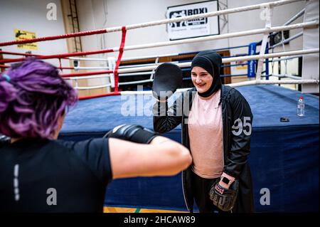 Berlin, Deutschland. 16th Dez 2021. Boxtrainerin Doha Taha Beydoun trainiert mit einer ihrer Boxer. Sie ist erst 20 Jahre alt. Verheiratet. Vier Monate schwanger. Muslim und ein Boxtrainer. Ihre Eltern emigrierten als Baby aus dem Libanon nach Deutschland. Doha Taha Beydoun scheint einigen „trange“ zu sein, sagt sie, weil ihre Nationalität, Religion und ihr Sport nicht übereinstimmen. Andere sehen sie als Vorbild, wie sie selbst sagt. "Ich Kämpfe gegen alle Vorurteile", sagt die junge Frau zuversichtlich. Quelle: Fabian Sommer/dpa/Alamy Live News Stockfoto