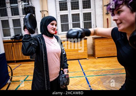 Berlin, Deutschland. 16th Dez 2021. Boxtrainerin Doha Taha Beydoun trainiert mit einer ihrer Boxer. Sie ist erst 20 Jahre alt. Verheiratet. Vier Monate schwanger. Muslim und ein Boxtrainer. Ihre Eltern emigrierten als Baby aus dem Libanon nach Deutschland. Doha Taha Beydoun scheint einigen „trange“ zu sein, sagt sie, weil ihre Nationalität, Religion und ihr Sport nicht übereinstimmen. Andere sehen sie als Vorbild, wie sie selbst sagt. "Ich Kämpfe gegen alle Vorurteile", sagt die junge Frau zuversichtlich. Quelle: Fabian Sommer/dpa/Alamy Live News Stockfoto